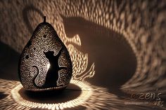 an artistically designed vase with a cat on it's side in the shadows