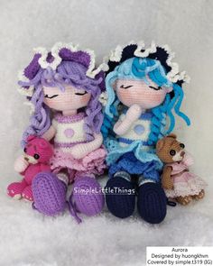 two crocheted dolls sitting next to each other on a white surface with snow