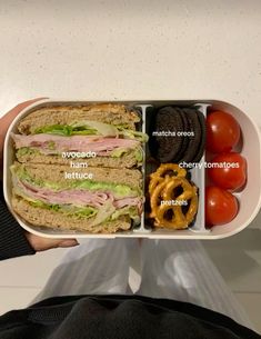 a person holding a tray with sandwiches and pretzels