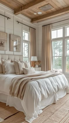 a large white bed sitting in a bedroom next to two windows