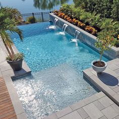 an outdoor swimming pool surrounded by trees and water features two lounge chairs on either side