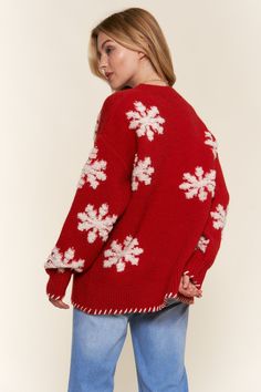 a woman wearing a red sweater with white snowflakes on the sleeves and back