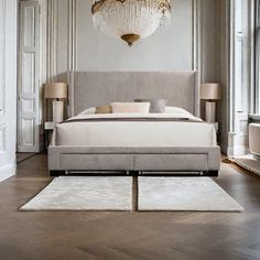 a bedroom with a large bed, chandelier and two lamps on the wall