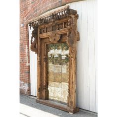 an old wooden mirror sitting on the side of a building next to a brick wall