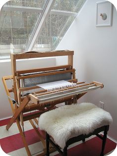 a piano sitting in front of a window next to a bench with a fur rug on it