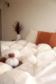 an unmade bed with white sheets and pillows