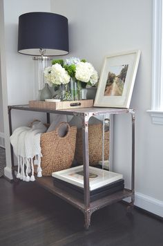 a table with some baskets and flowers on it next to a wall mounted photo frame