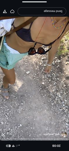 a woman in blue and white swimsuit standing next to a horse on dirt ground