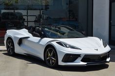 a white sports car parked in front of a building