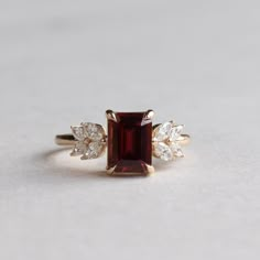 Metal: 14K Yellow Gold Stone: Emerald Cut Garnet  Stone Weight: 1.5 carat Stone Size: 5.75mm x 7.79mm Accent Stones: Natural Diamonds Accent Shapes: Marquise  Shank: 1.6mm Elegant Red Birthstone Ring With Vvs Clarity, Ruby Ring Designs, Red Engagement Ring, Antique Ruby Ring, Wedding Rings Emerald Cut, Garnet Wedding Rings, Garnet Wedding, Garnet And Diamond Ring, Red Garnet Ring