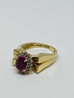 "This is a vintage 14K yellow gold, ruby, and diamond statement ring. The sharp edges of this ring give it a polished and refined look. Material(s): 14K yellow gold + (1) oval ruby + several diamonds Weight: 5.3 grams Flaws (if any): None to mention Marking(s): \"14K\" BAND SIZE 4 3/4 (or 4.75)" Vintage Ruby Ring With Diamond Accents, Vintage Oval Ruby Ring With Vvs Clarity, Vintage Ruby Cluster Ring For Formal Occasions, Vintage Ruby Cluster Ring For Formal Events, Vintage Ruby Rings With Diamond Accents, Vintage Ruby Diamond Ring Stamped 14k, Vintage Ruby Diamond Ring In 14k Gold, Vintage Ruby Ring With Vvs Clarity, Vintage Gold Ruby Ring With Vvs Clarity