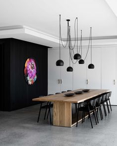 a large wooden table surrounded by black chairs in a room with white walls and flooring