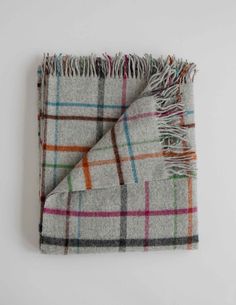 a plaid blanket folded on top of a white wall