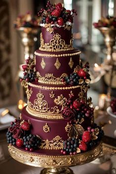 a three tiered cake decorated with berries and gold