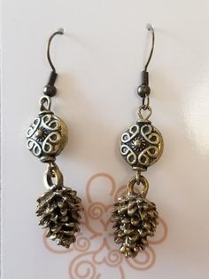 One-of-a-kind antique brass beaded pine cone earrings with hypoallergenic and nickel-free hooks. Details: One of a kind Primary metal: Antique brass Intricate charm designs Hypoallergenic and nickel-free hooks Adorable piece for daily wear For more details, questions or customizations, contact us anytime online, by phone, or in person. Thank you! Social Media: @Shopdearbritt Email: Shop@dearbritt.com.Call/Text: 405-762-9761Location: 901 S Main St. Stillwater, OK 74074 Pine Cone Earrings, Jewelry Repair, Pine Cone, Still Water, Pine Cones, Pho, Custom Jewelry, Antique Brass, Ring Earrings