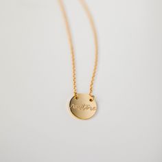 Gold necklace with the word restore written on circular pendant.