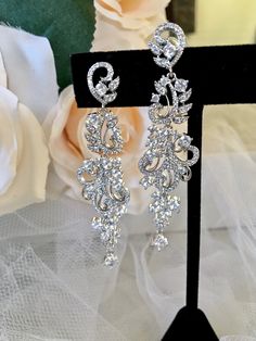 A delightfully unique pair of bridal earrings with an incredible sparkle! Lightweight, the earrings are adorned with high grade cubic zirconia that capture the light in a dazzling array of sparkles, and are rhodium plated for a bright finish which enhances the intricate detailing and conveys a modern take on old elegance. Length: 2.5" (approx. 6.35cm). Hypoallergenic - lead, nickel and cadmium free. This exquisite design will add a touch of sophistication to any wedding gown or formal ensemble. Cubic Zirconia Bridal Earrings, Silver Wedding Jewelry, Bridal Earrings, Exquisite Design, Wedding Gown, Rhodium Plated, High Grade, Wedding Jewelry, Wedding Gowns