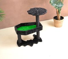 a cat tree that is on top of a table next to a potted plant