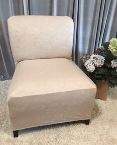 a white chair sitting on top of a carpeted floor next to a vase with flowers