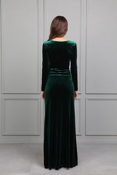 a woman wearing a green velvet dress with long sleeves and a slited neckline