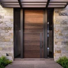 the front door to a modern home with stone walls and wood trimming on it