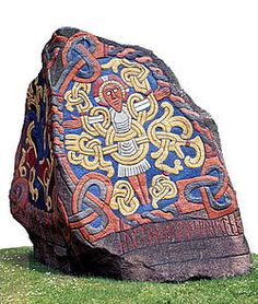 a large rock with an intricate design on it's side in the middle of a grassy area