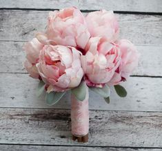 a bouquet of pink flowers sitting on top of a white wooden floor next to a wall