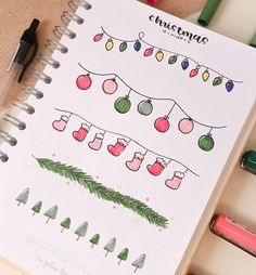 a notebook with christmas decorations on it next to some markers and pencils in the background