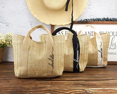 three jute bags sitting on top of a wooden table next to a straw hat