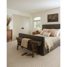 a bedroom with a bed, dresser and window in the corner that has a rug on the floor