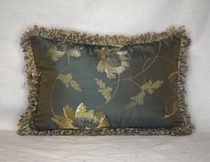 a green pillow with gold leaves on it