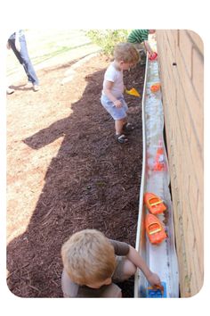 two young boys playing with toys in the dirt