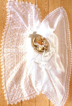 a white crocheted doily on a wooden floor with shells in the center