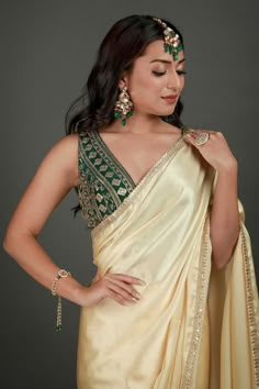 Embrace the beauty of the Cassandra Cream Satin Gold Trim One Minute Saree made with a gold sequin border. Styled with a art silk blouse in bottle green color. Perfect for your next festive occasion. Product Features: Saree Color: Cream Blouse Color: Bottle Green Saree Fabric: Satin Blend Blouse Fabric: Art Silk Blouse In Green Saree Work: Gold Sequin Border Saree Wash Care: Dry Clean Occasion: Party , Cocktail Party ,Wedding Reception Package Content: Saree Disclaimer: There will be slight diff Gold Pre-draped Saree With Cutdana For Party, Gold Pre-draped Saree For Navratri Party, Gold Embellished Tissue Silk Saree, Elegant Green Dola Silk Choli, Festive Party Wear Raw Silk Blouse Piece, Festive Party Wear Blouse In Raw Silk, Gold Cutdana Traditional Party Wear, Elegant Gold Blouse Piece With Mirror Work, Gold Blouse Piece With Mirror Work For Eid