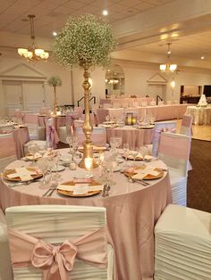 the tables are set up for a formal function with pink linens and gold chargers