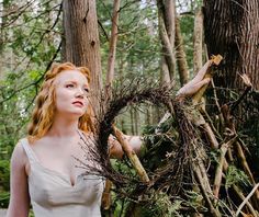 a woman standing in the woods holding branches