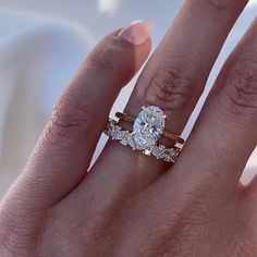 a woman's hand with two engagement rings on top of her finger and the other half