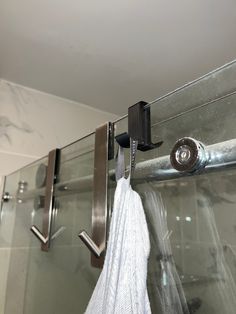 a towel hanging on the side of a glass shower door with metal bars and hooks