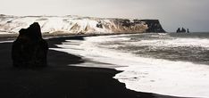 the black sand beach is covered in white snow