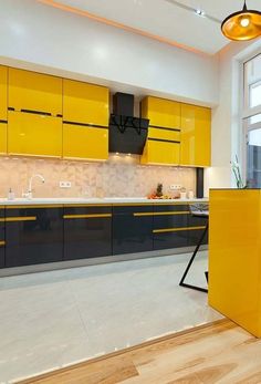 a kitchen with yellow cabinets and black counter tops in the middle of an open floor plan