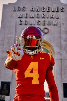 a man wearing a football uniform and holding his hand up in front of the los angeles memorial museum