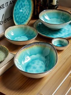 four blue dishes sitting on top of a wooden table next to a cupcake tin