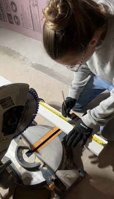 a woman is working on a piece of wood with a circular sawtoothing machine