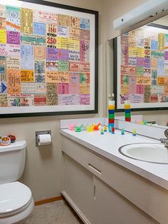 a bathroom with two sinks, a toilet and a large framed poster on the wall