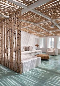 a living room filled with white furniture and lots of birch trees in the ceiling area