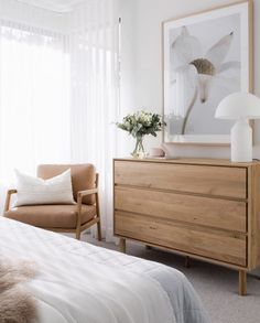 a bedroom scene with focus on the bed and dresser, which has a flower arrangement