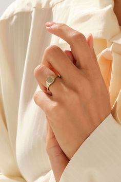 a woman's hand wearing a gold ring with a heart shaped stone on it