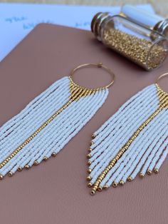 "Beaded Fringe Earrings  I call this pair \"Solaris\". These are the first pair in my \"White Collection\" and would be perfect as bridal earrings or accompanying a white flowing summer dress. The earrings were made with high quality Japanese glass seed beads and 14k gold filled findings, made in USA.  - Length: 3 1/2 inch from top of ear wire - Width: 1 inch  To find out more about the inspiration behind these earrings, please visit dordean.com (coming soon). - Returns: For hygiene reasons, earrings cannot be returned or exchanged. Please send me a message in case of any issues. Please note that due to different screens and screen settings, colors may vary slightly from the actual product. To enjoy these earrings for many years to come, please store them away from direct sunlight. Do not White Hoop Earrings For Celebration, Bohemian White Dangle Pearl Earrings, White Bohemian Dangle Pearl Earrings, Elegant White Round Bead Earrings, Elegant White Hoop Earrings For Celebration, White Bohemian Long Drop Earrings, White Dangle Hoop Earrings With Dangling Beads, White Hoop Earrings With Dangling Beads, White Hoop Earrings For Pierced Ears For Celebration