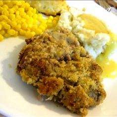 a white plate topped with meat and mashed potatoes next to corn on the cob