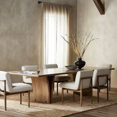 a dining room table with chairs and a vase on the floor in front of it